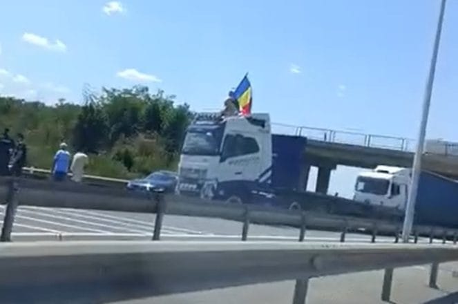 Protest pe A1: șofer de TIR blochează autostrada fluturând steagul României; traficul reluat, manifestanții reținuți de poliție Protest pe A1: șofer de TIR blochează autostrada fluturând steagul României; traficul reluat, manifestanții reținuți de poliție